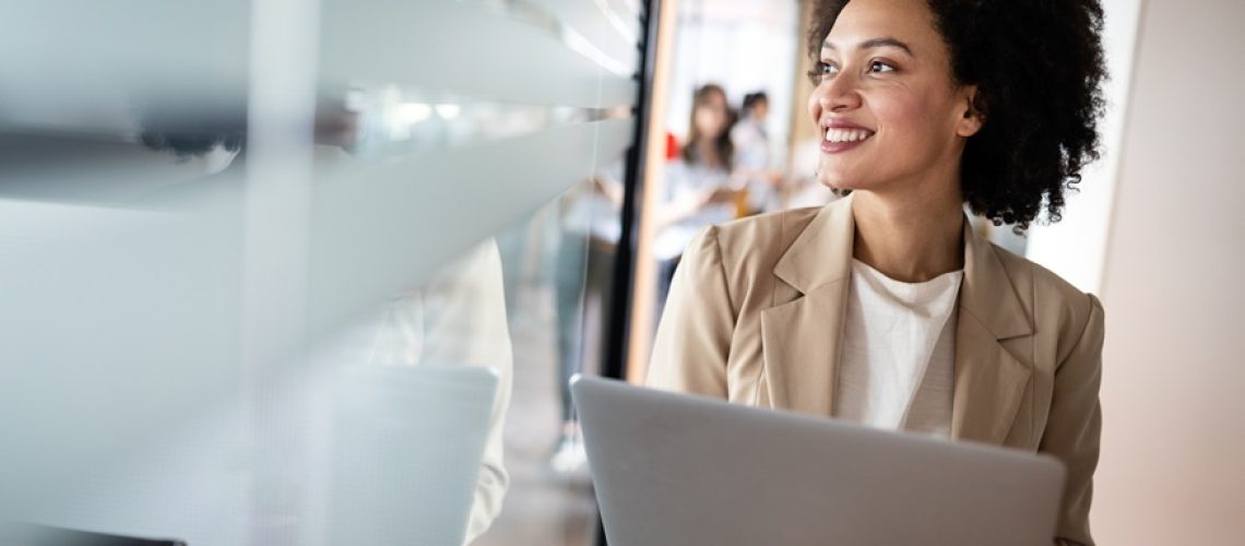 Portrait of an attractive young businesswoman smiling while standing by windows in a modern office